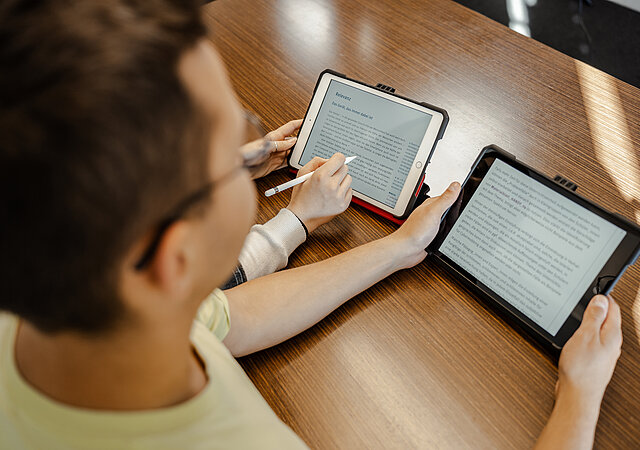 Schüler liest Text auf Tablet für den Unterricht.